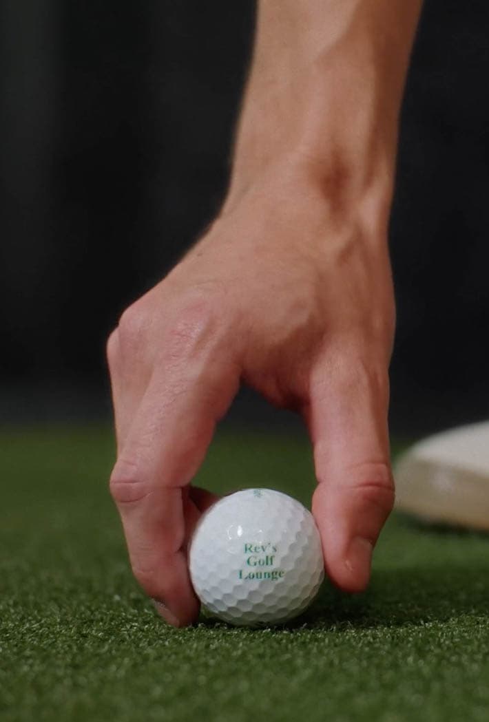 golfer mid swing in a simulator bay